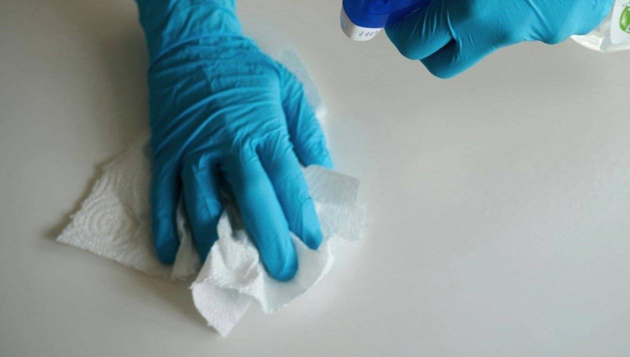 A gloved hand wiping a white surface during a deep clean