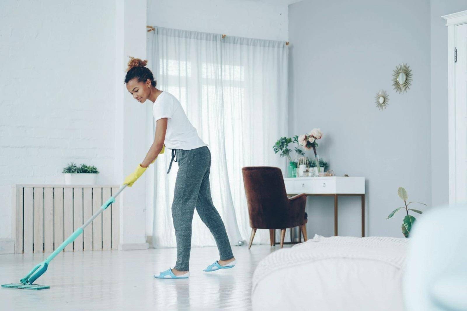 A cleaner mopping a bright living room floor